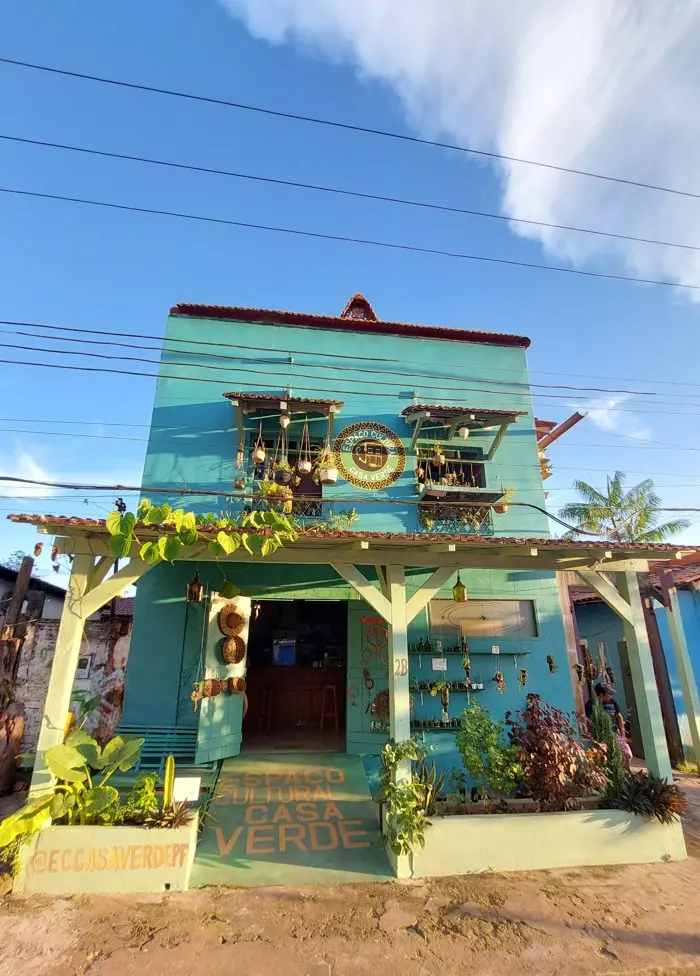 Fachada do Espaço Cultural Casa Verde, azul e cheia de plantas